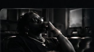 Recording artist seated in a dark studio